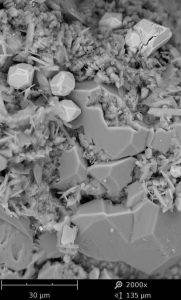 SEM Image showing clays on a grain surface, associated with quartz overgrowths and pyrite euhedra.